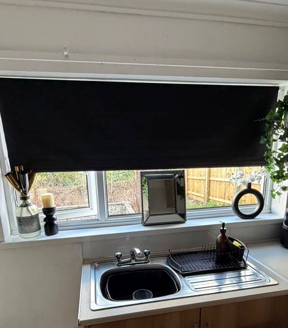 Same kitchen window with a dark roller blind fitted