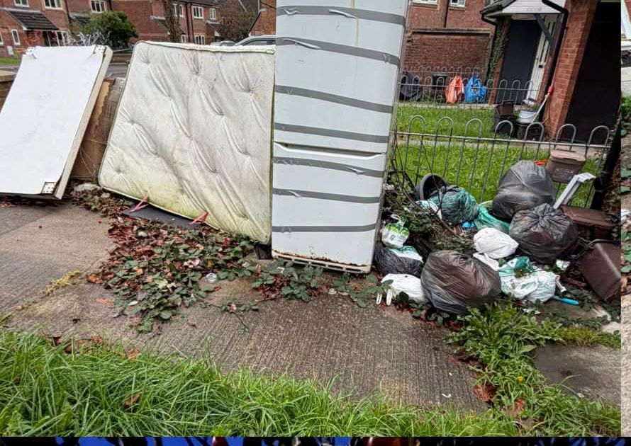 Old mattresses, fridge and bags piled in a front garden