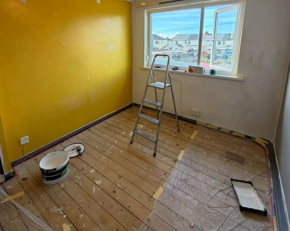 Bedroom with a bright yellow wall, stepladder and paint tins