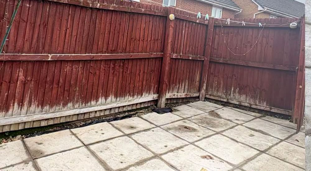 Weathered wooden fence panels around a paved yard