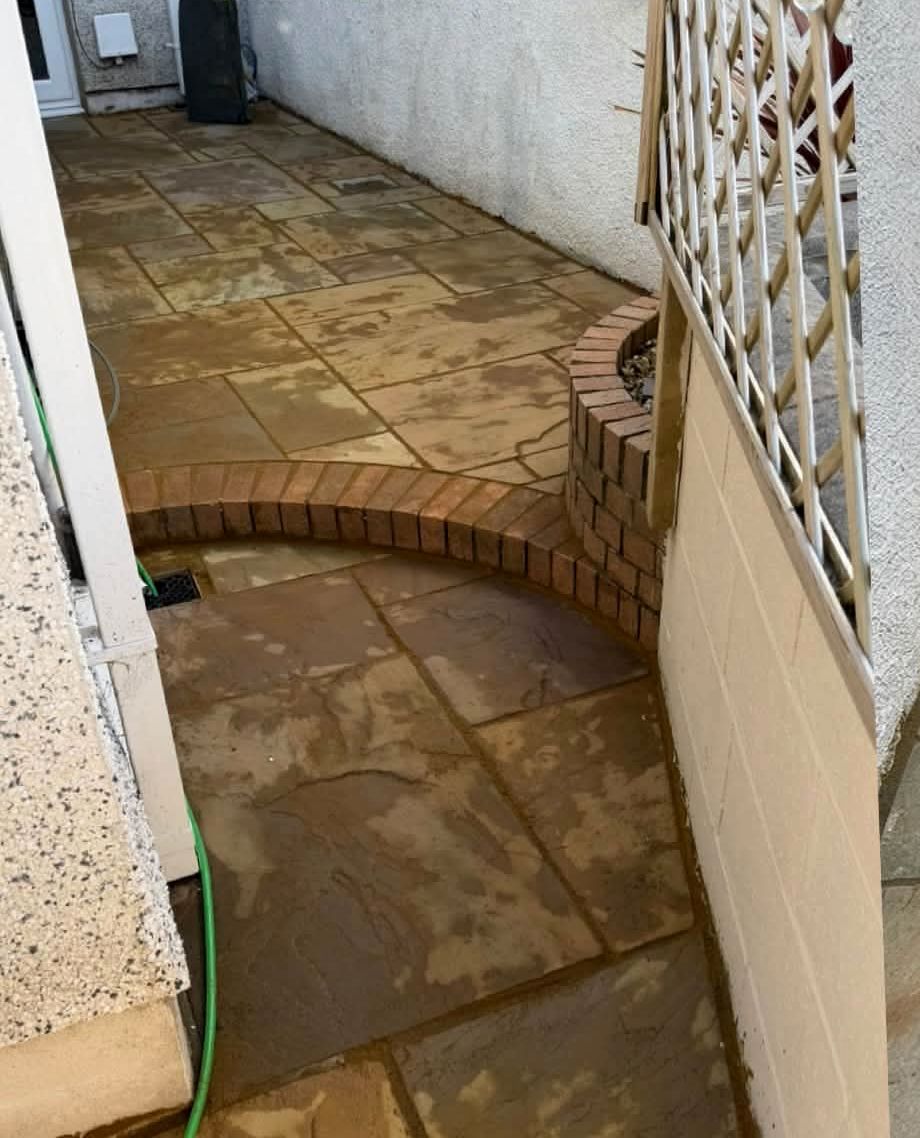 Dirty, stained sandstone patio by a side wall